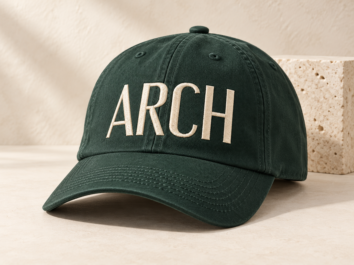 Generated concept of a forest-green cotton cap with cream ARCH embroidery on a pale stone surface.